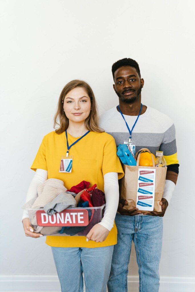 A black man and caucasian woman holding donation boxes, highlighting diversity and charity.
